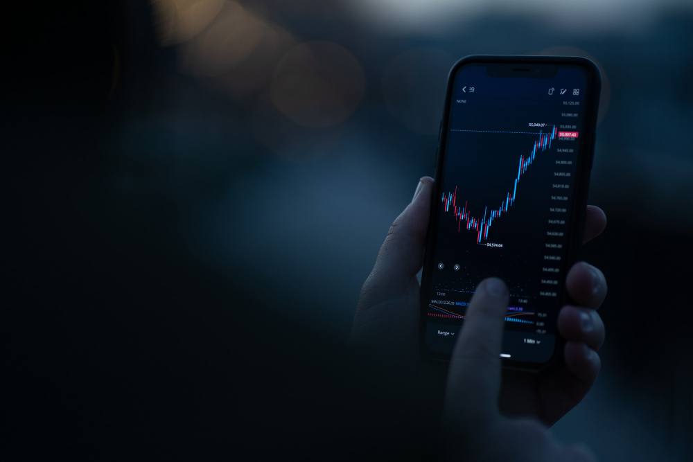 Bild von Smartphone in Hand mit Börse und Aktienkurse